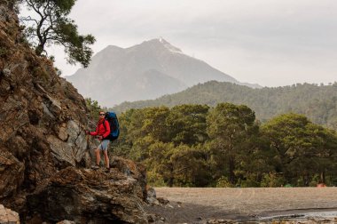 Yürüyüş sırt çantası ile kaya üzerinde duran güneş gözlüğü kadın
