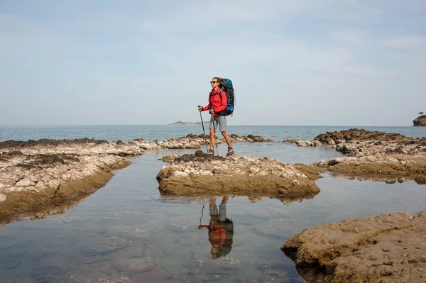 Flicka stående på berget på havet med vandring ryggsäck — Stockfoto