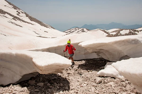 Trekker femenino con bastones entre grumos de nieve — Foto de Stock