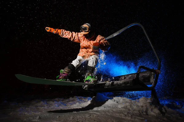 Homem snowboarder vestido com um sportswear laranja saltando do funicular — Fotografia de Stock