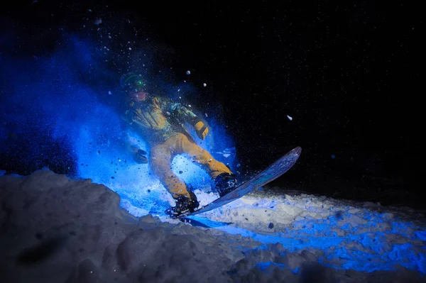 Actieve mannelijke snowboarder gekleed in een gele sportkleding voert trucjes uit op de sneeuw helling — Stockfoto