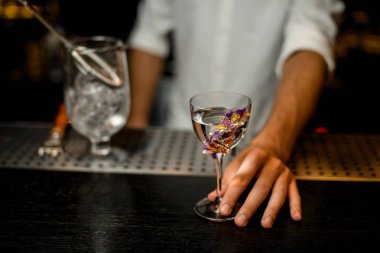 Çiçeklerle süslenmiş camda kokteyl servisi yapan profesyonel barmen