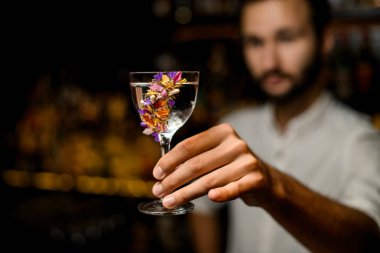Çiçeklerle süslenmiş camda kokteyl servisi yapan çekici barmen