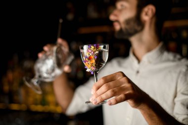 Çiçeklerle süslenmiş cam bir kokteyl hizmet sakallı çekici barmen