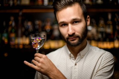 Barmen çiçeklerle süslenmiş cam bir kokteyl sunan