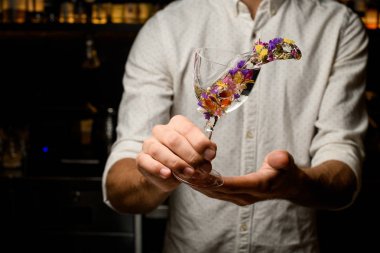 Profesyonel barmen çiçeklerle süslenmiş cam bir kokteyl ile bir sıçrama yapma
