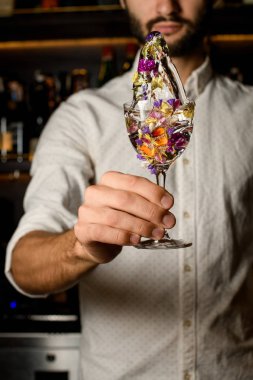 Profesyonel erkek barmen çiçeklerle süslenmiş cam bir kokteyl ile bir sıçrama yapma