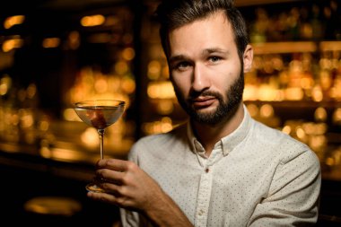 Pembe buz küpü ile süslenmiş cam bir kokteyl sunan çekici barmen