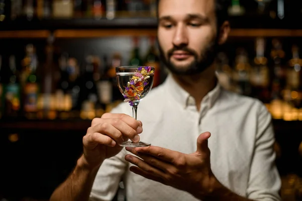 Çiçeklerle süslenmiş camda kokteyl sunan çekici barmen — Stok fotoğraf