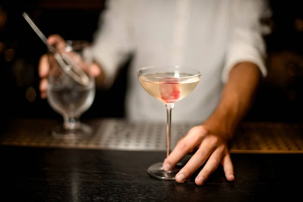 Professioneller Barkeeper serviert einen Cocktail im Glas mit rosa Eiswürfel hält eine Tasse mit Eis dekoriert — Stockfoto