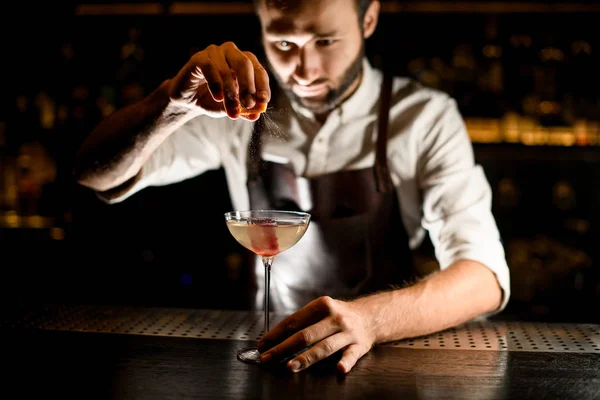 Mannelijke barman serveert een cocktail in het glas het toevoegen van een citroensap — Stockfoto