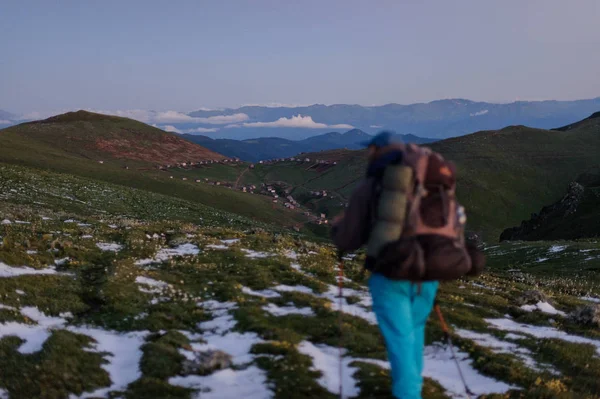 后视男子在雪地上行走与登山背包和棍子的雪残 — 图库照片