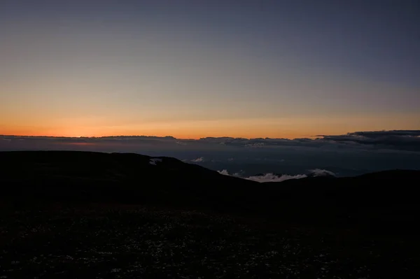 Paisagem das colinas cobertas de grama no fundo do céu claro no pôr do sol — Fotografia de Stock