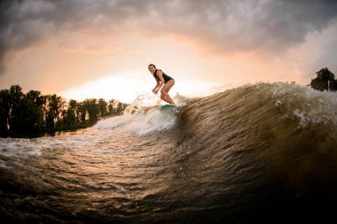 Girl riding on the wakeboard on the river clipart