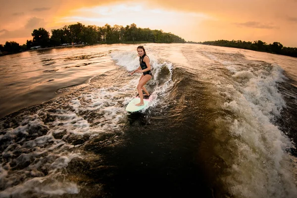 Ragazza sportiva cavalcando sul wakeboard sul fiume sull'onda del motoscafo — Foto Stock