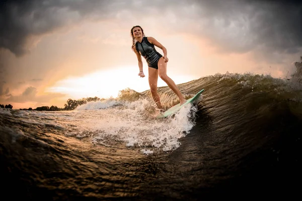 Slim fit girl riding on the wakeboard on the river on the wave — Stock Photo, Image