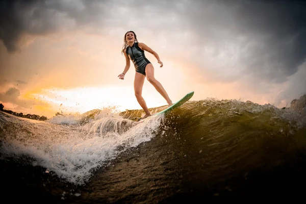 Morena chica cabalgando en el wakeboard en el río en la ola —  Fotos de Stock