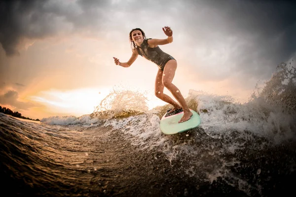 Skinny meisje rijden op het Wakeboard op de rivier op de Golf op de buig knieën — Stockfoto