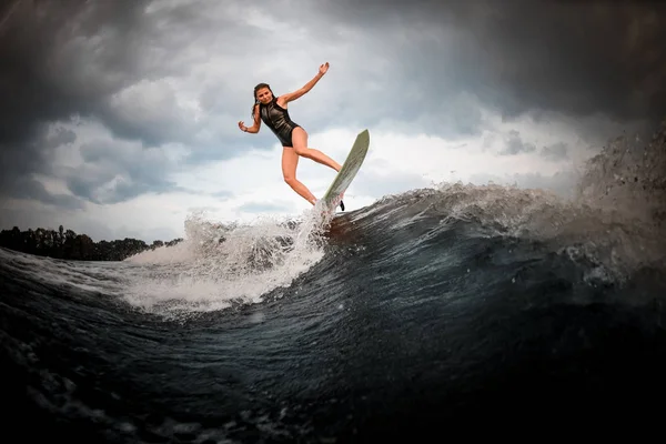 Спортивна дівчина стрибає на весло на річці на фоні дерев, що піднімаються руками — стокове фото