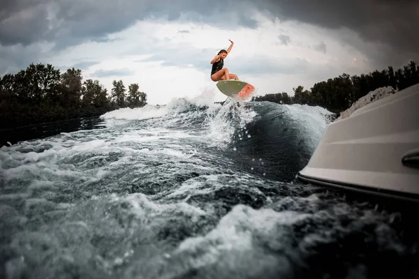 Sportowa dziewczyna skoki na wakeboard na rzece na fali motorówki — Zdjęcie stockowe