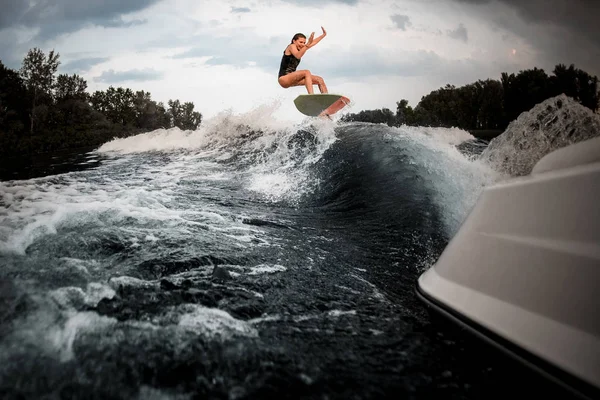 Дівчина стрибає на весло на річці на хвилі моторного човна — стокове фото