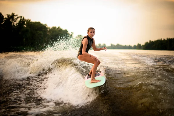 Mujer cabalgando en el wakeboard en el río en el fondo de los árboles —  Fotos de Stock