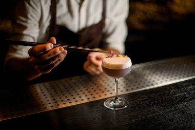 Erkek barmen sarı ve mor çiçek yaprakları ile lezzetli açık mor renkli kokteyl dekore