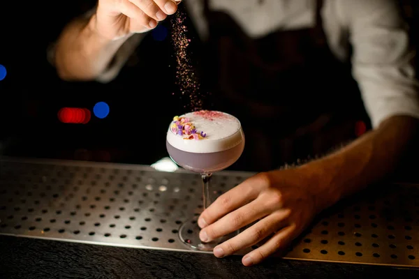 Professional bartender sprinkling on the cocktail decorated with petals a shredded flowers — Stock Photo, Image