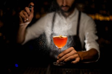 Barmen karamelize limon dilimi ve üzerine biraz sarı çiçek püskürtme ile bir kokteyl hizmet