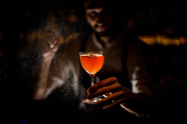Erkek barmen karanlıkta üzerine püskürten kahverengi turuncu kokteyl hizmet