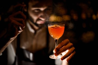 Profesyonel barmen karanlıkta üzerine püskürtme kahverengi turuncu kokteyl hizmet