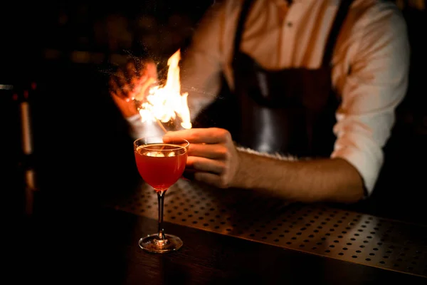 Профессиональный бармен, подающий коктейль в стекле опрыскивая горящий спичку лимонным соком — стоковое фото