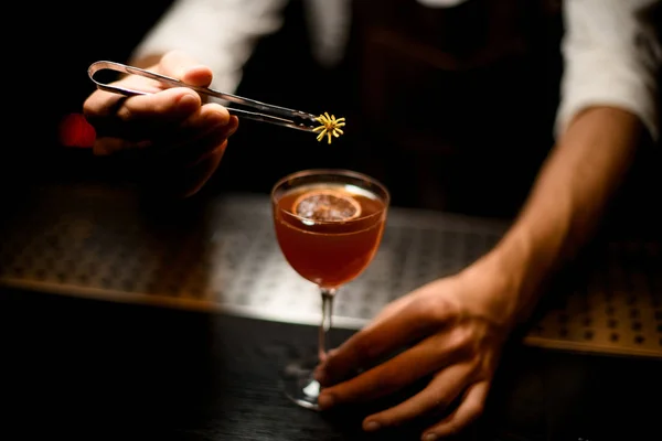 Professionell bartender som serverar en cocktail i glaset med en karamelliserad citronskiva som lägger till en gul blomma — Stockfoto