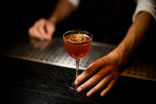 Barista che serve un cocktail nel bicchiere con una fetta di limone caramellato e un piccolo fiore giallo — Foto Stock