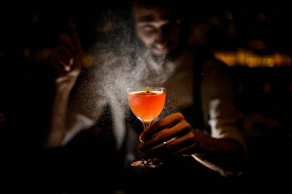 Professionell bartender serverar en cocktail med en citronskiva och en liten gul blomma sprutning på den i mörkret — Stockfoto
