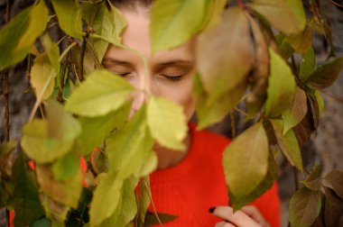 Üzüm tırmanma yapraklar arasında duran turuncu kazak kadın