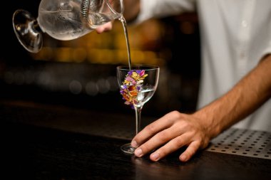 Barmen süzgeç ile camdan kokteyl döker