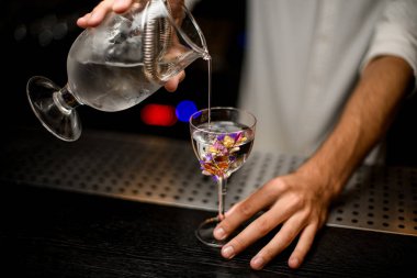 Barmen süzgeç ile camdan kokteyl dökme