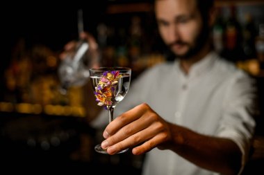 Sakallı barmen cam alkol ve süzgeç tutar