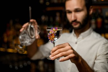 Camda alkol ve süzgeç tutan sakallı barmen