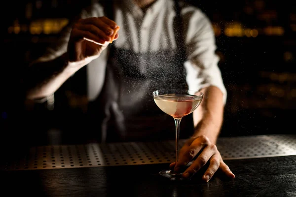 Bartender sprinkling an alcohol in glass on counter — 스톡 사진