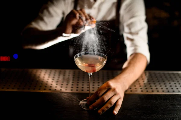 Bartender sprinkles cocktail in glass on a counter — Stock Fotó