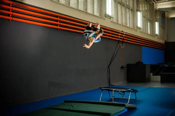 Człowiek skoki z trampoliny do maty w siłowni — Zdjęcie stockowe