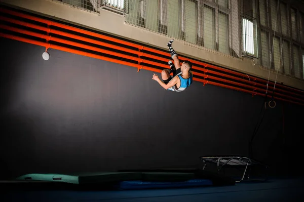 Junger Mann in Sokcs springt in der Turnhalle vom Trampolin auf die Matte — Stockfoto