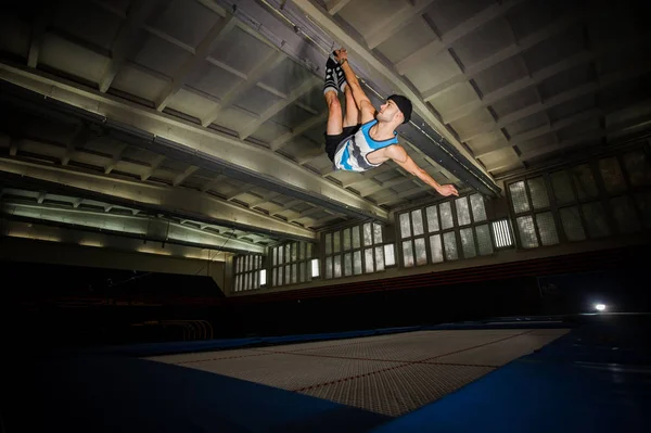 Junge macht Tricks auf dem Trampolin in der Turnhalle — Stockfoto