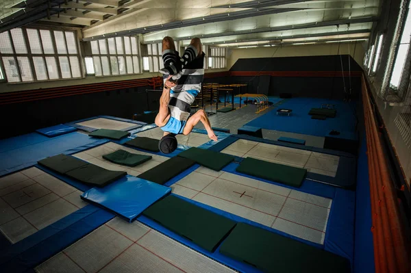 Junge macht komplizierten Flip auf dem Trampolin in der Turnhalle — Stockfoto
