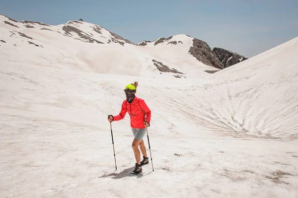 ハイキングスティックでタタリ山の汚れた雪の上を歩く女性 — ストック写真