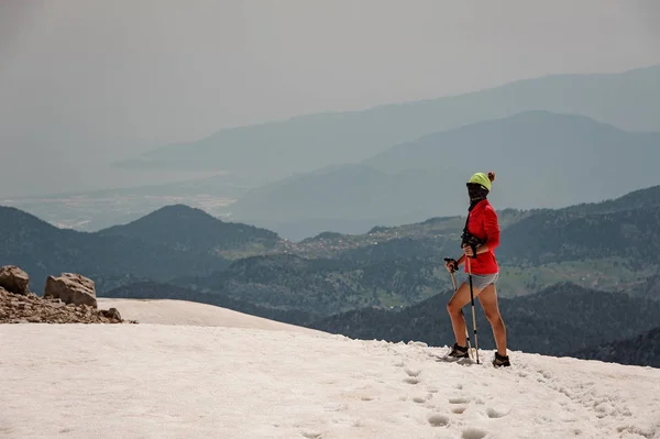 ハイキングスティックでタタリ山の汚れた雪の上に立つスポーティな女性 — ストック写真