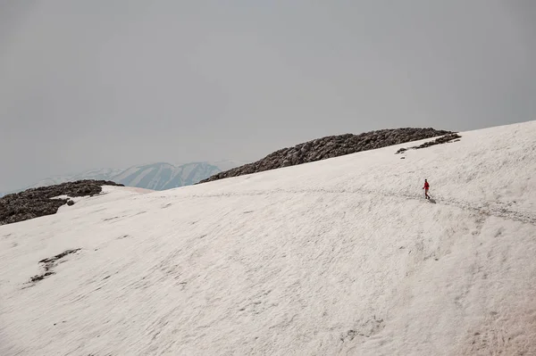 Woman in far walking on the dirty snow on the Tahtali mountain with hiking sticks — Stock Photo, Image