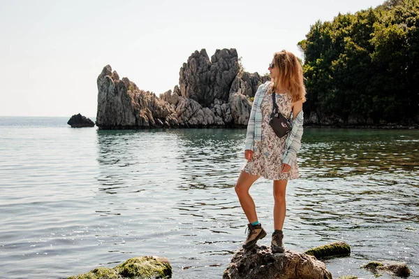 Девушка в светлом платье, стоящая на скале у моря — стоковое фото